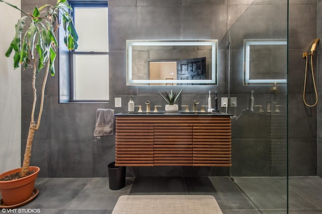 bathroom featuring double vanity, walk in shower, a sink, and tile patterned floors