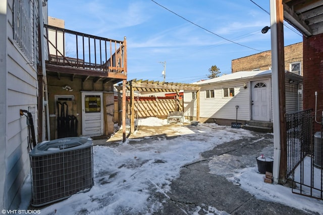 yard covered in snow with entry steps, a pergola, fence, and central AC unit