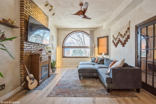 sitting room featuring a fireplace with flush hearth, wood finished floors, a ceiling fan, and baseboards