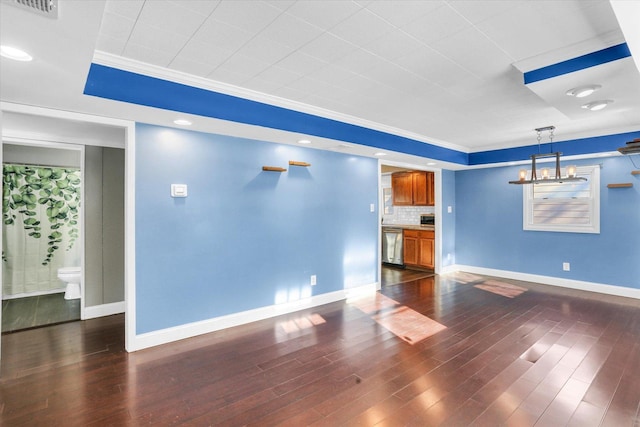 unfurnished living room with dark hardwood / wood-style floors, crown molding, and an inviting chandelier