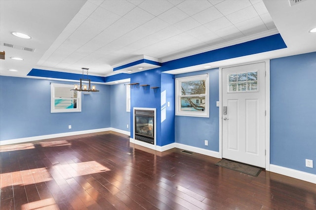 unfurnished living room featuring dark hardwood / wood-style flooring, crown molding, and a chandelier