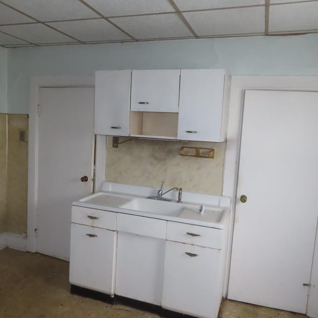 kitchen with a drop ceiling and white cabinetry