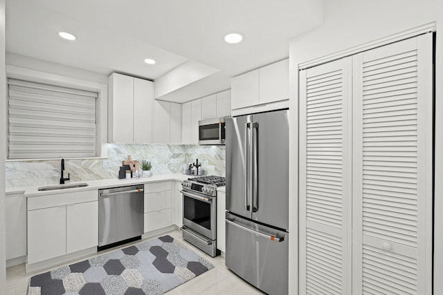 kitchen featuring sink, decorative backsplash, stainless steel appliances, and white cabinets