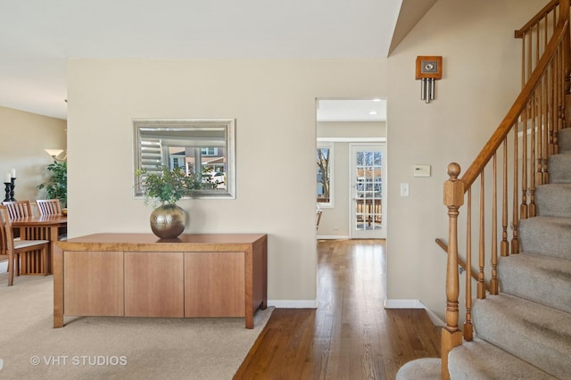 foyer entrance with a wealth of natural light, baseboards, light wood-style flooring, and stairs