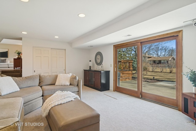 living area with recessed lighting, visible vents, and light carpet