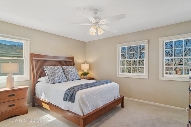 bedroom with light colored carpet, a ceiling fan, baseboards, and multiple windows