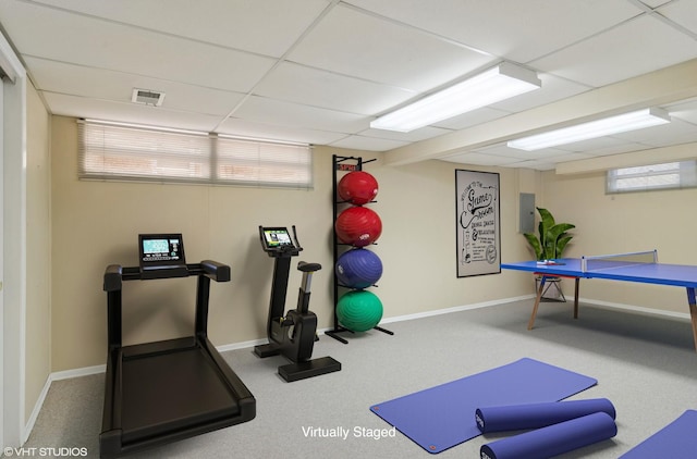 exercise area featuring electric panel, a healthy amount of sunlight, baseboards, and a drop ceiling