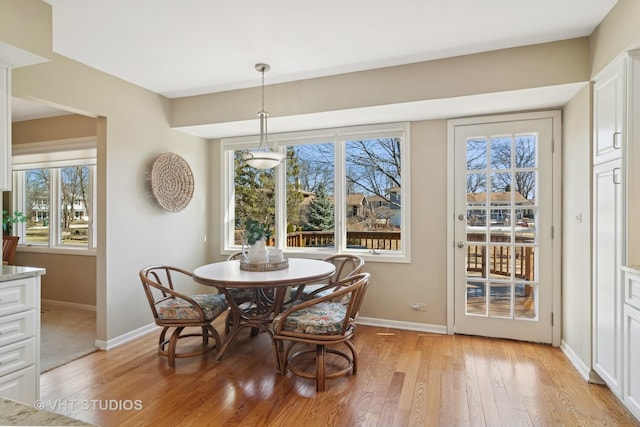 dining space featuring light wood-style flooring and baseboards