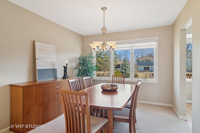 dining space with baseboards, light colored carpet, and an inviting chandelier