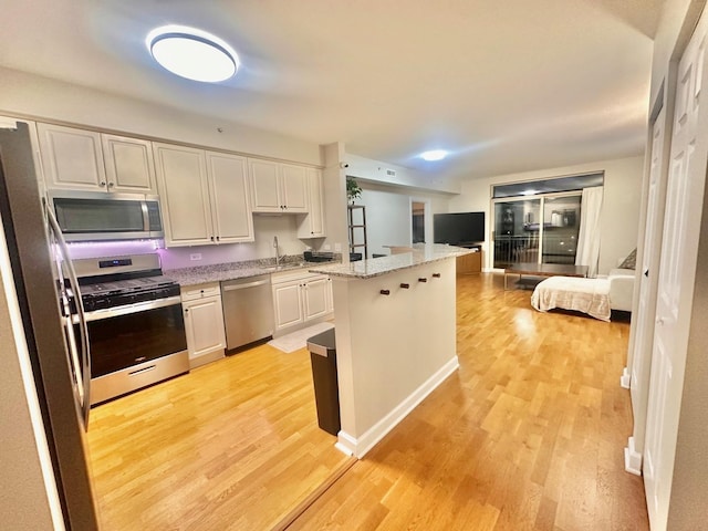 kitchen featuring white cabinets, a center island, light wood-type flooring, and appliances with stainless steel finishes