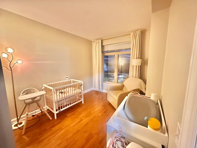 bedroom featuring a nursery area and hardwood / wood-style floors