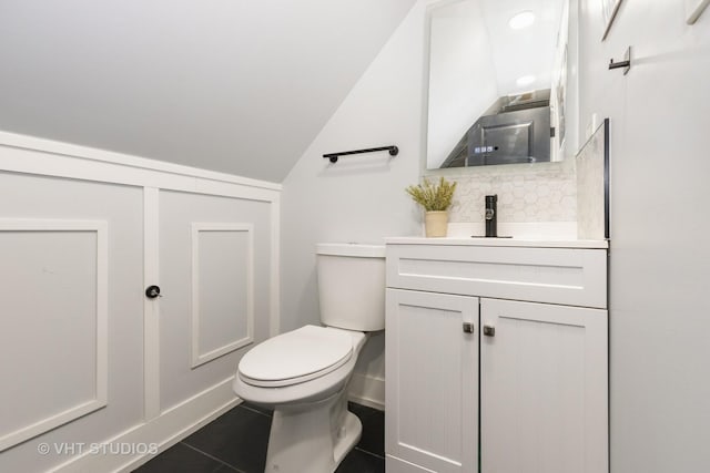 bathroom with tile patterned floors, vanity, lofted ceiling, and toilet