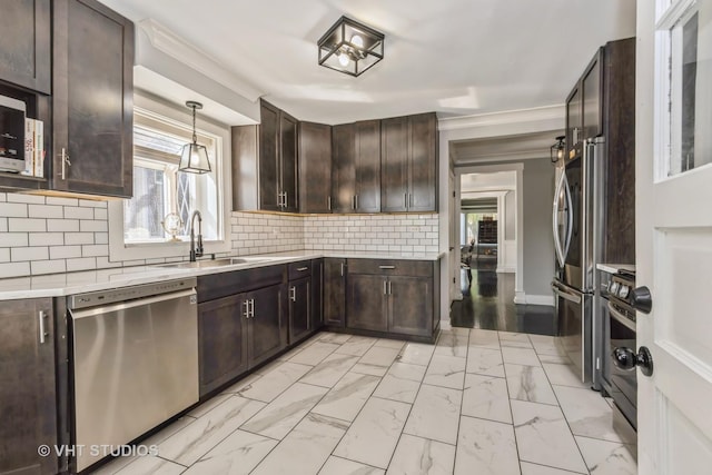 kitchen featuring appliances with stainless steel finishes, dark brown cabinetry, hanging light fixtures, and sink