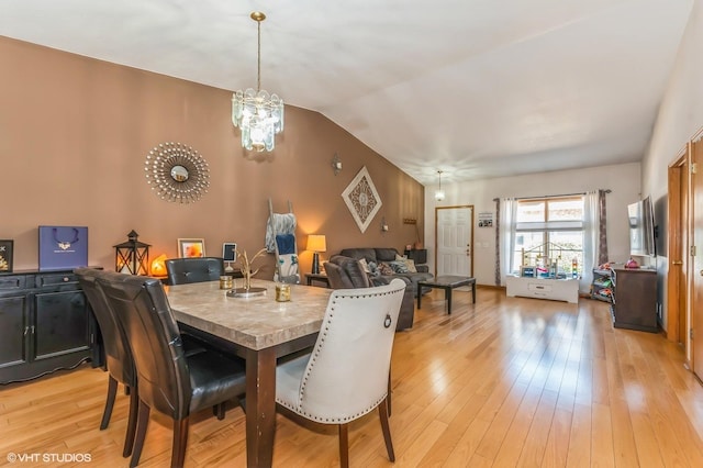 dining space featuring a chandelier, vaulted ceiling, and light wood-type flooring