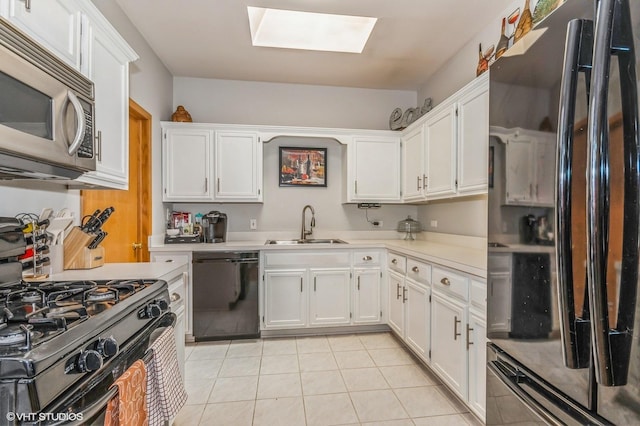 kitchen featuring black appliances, white cabinets, sink, a skylight, and light tile patterned floors