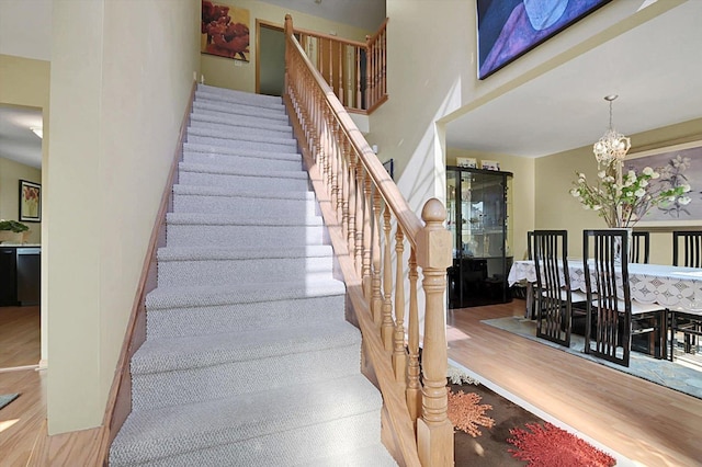 staircase with hardwood / wood-style floors and a chandelier