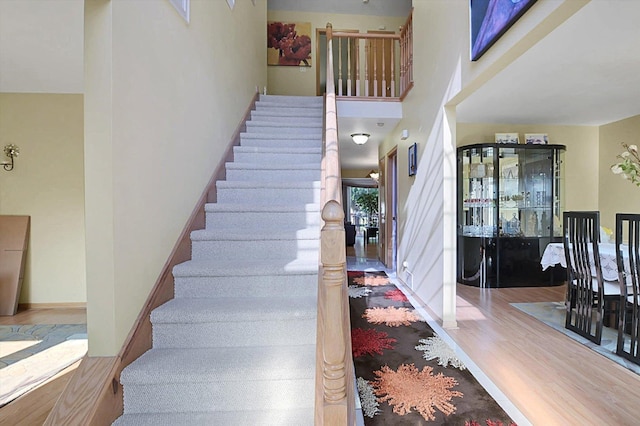 stairs with a high ceiling and hardwood / wood-style flooring