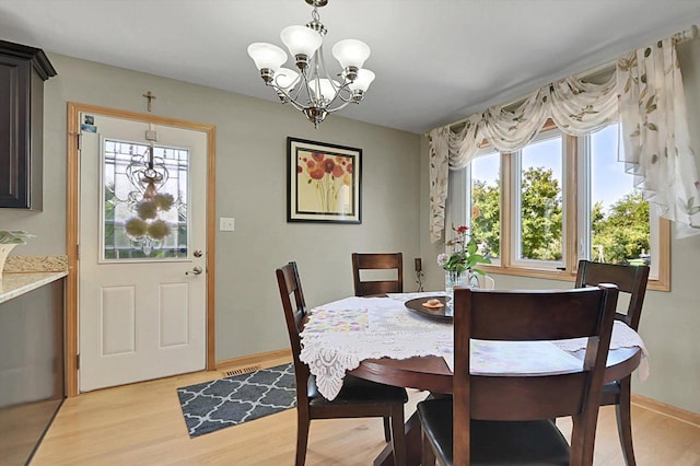 dining space featuring a notable chandelier and light wood-type flooring