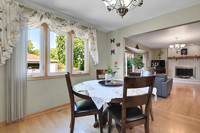 dining area with a fireplace, light wood-type flooring, and a chandelier