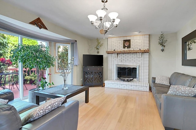 living room featuring a brick fireplace, wood-type flooring, and an inviting chandelier