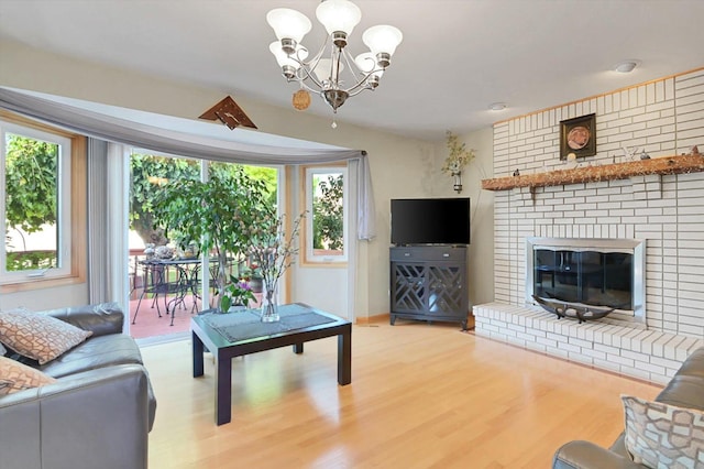 living room with a brick fireplace, hardwood / wood-style flooring, a healthy amount of sunlight, and an inviting chandelier