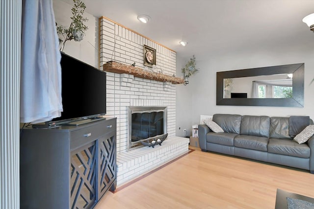 living room with wood-type flooring and a brick fireplace