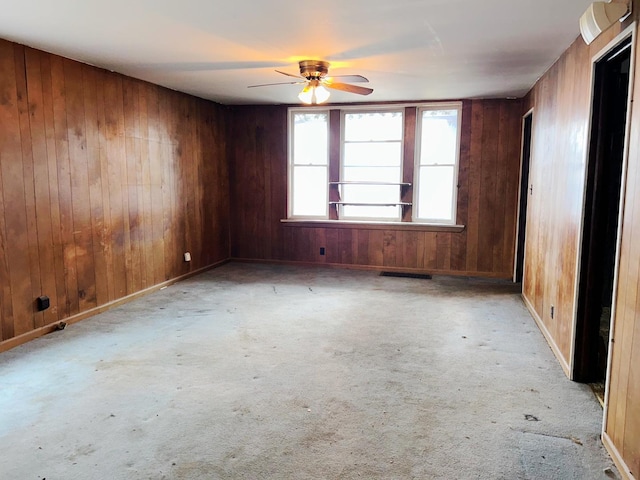 empty room featuring ceiling fan and wood walls