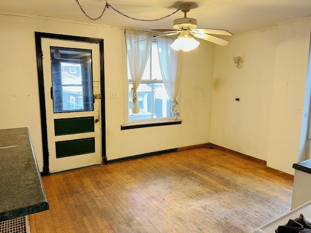 interior space featuring ceiling fan, wood-type flooring, and crown molding