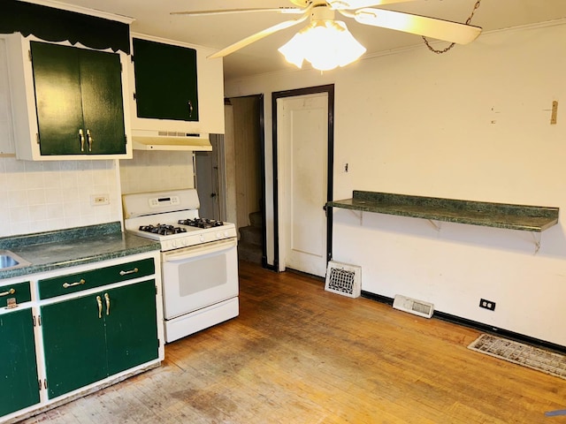 kitchen featuring backsplash, ceiling fan, green cabinetry, white range with gas stovetop, and range hood