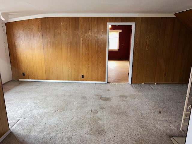 empty room featuring light carpet and wood walls