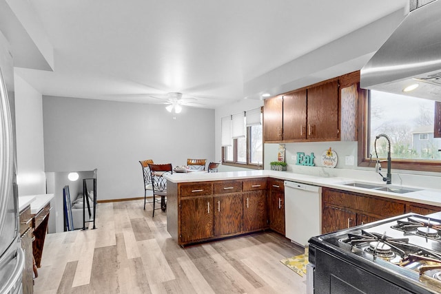 kitchen with dishwasher, sink, kitchen peninsula, range, and extractor fan