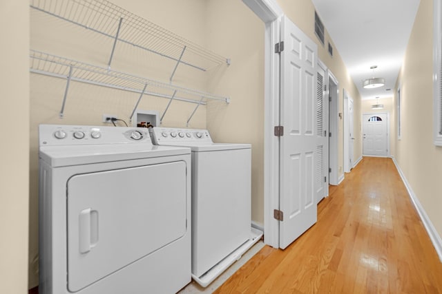 washroom with separate washer and dryer and light wood-type flooring