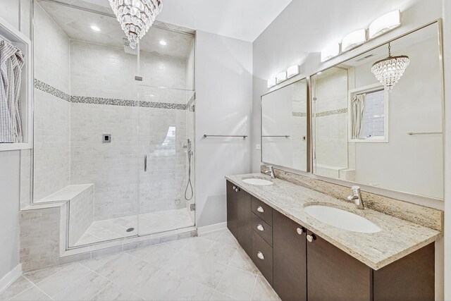 bathroom with tile patterned flooring, an inviting chandelier, an enclosed shower, and vanity