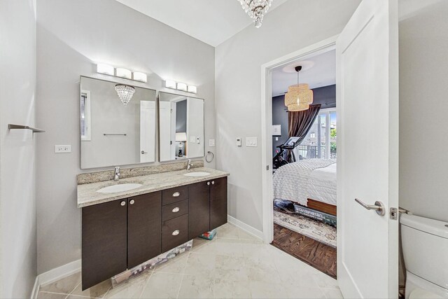 bathroom with an inviting chandelier, vanity, and toilet