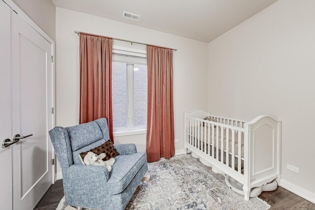 bedroom with hardwood / wood-style floors and a nursery area