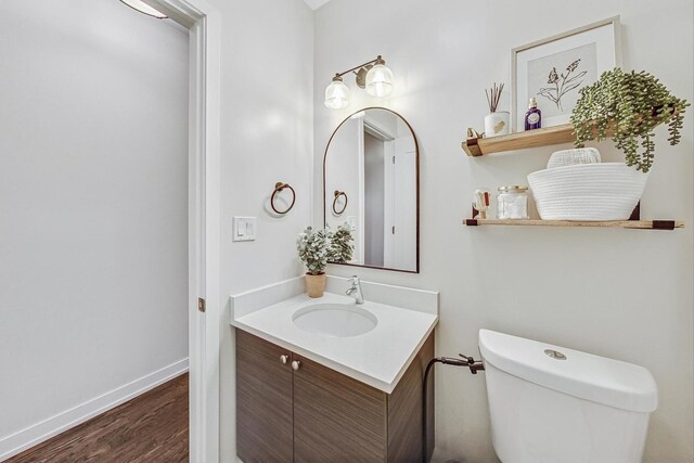 bathroom with wood-type flooring, vanity, and toilet