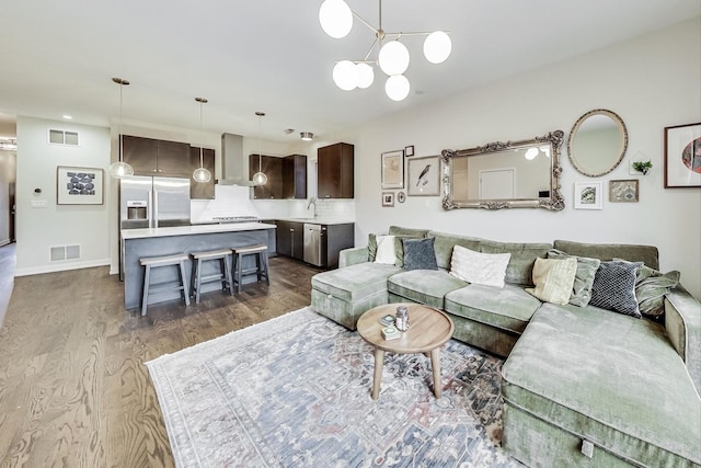 living room with sink, an inviting chandelier, and dark hardwood / wood-style floors