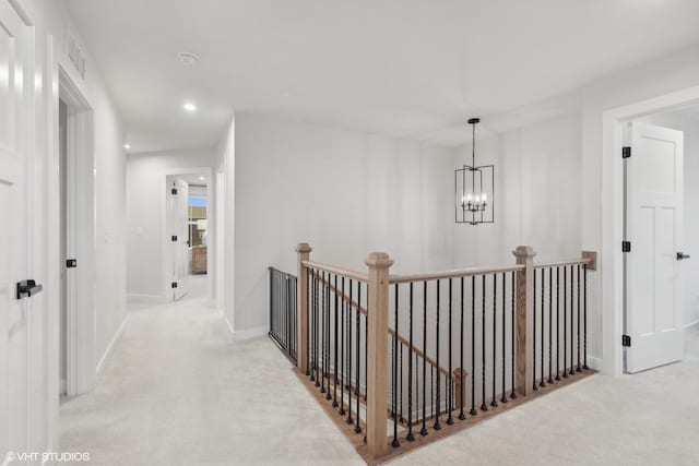 hall featuring light colored carpet and a chandelier