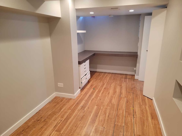 walk in closet with light wood finished floors