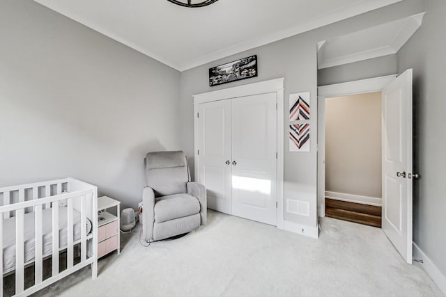 bedroom featuring a crib, crown molding, and light colored carpet