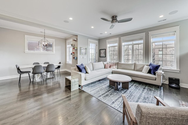 living room with ceiling fan with notable chandelier, crown molding, and dark hardwood / wood-style flooring