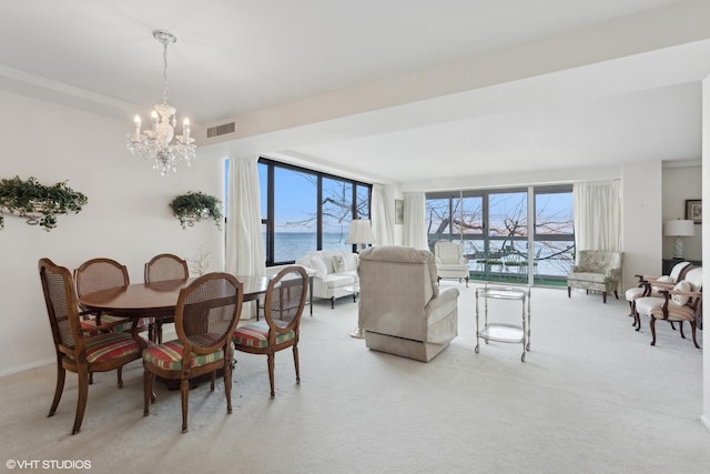 carpeted dining area with a chandelier, a water view, and expansive windows