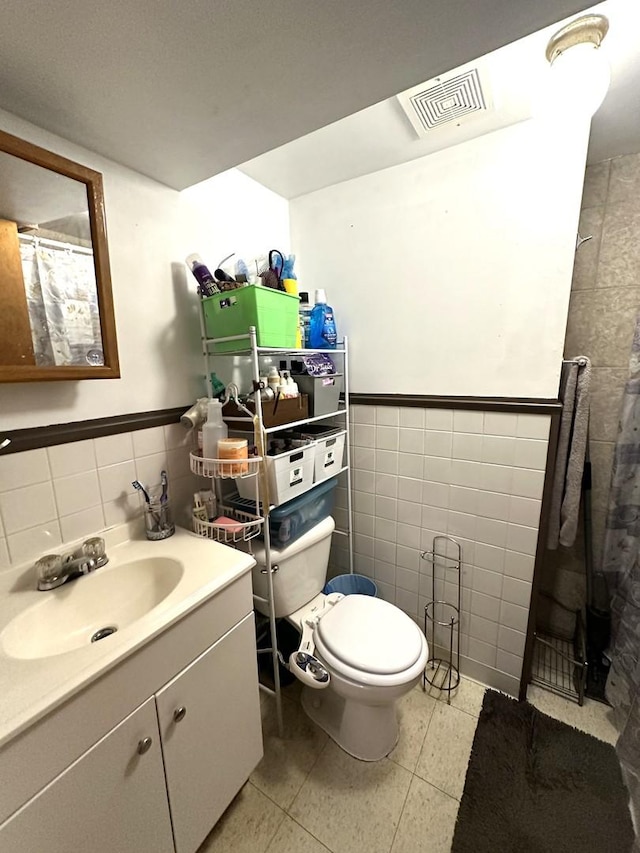 bathroom featuring toilet, vanity, and tile walls