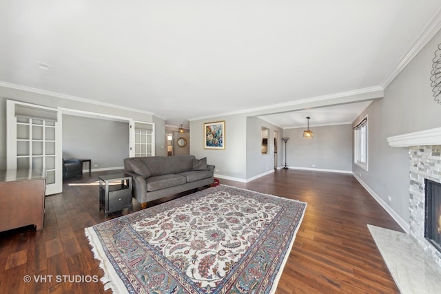 living room with dark wood-type flooring, ornamental molding, and a stone fireplace