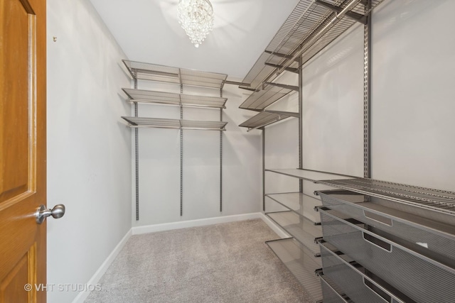 spacious closet featuring light colored carpet and a chandelier