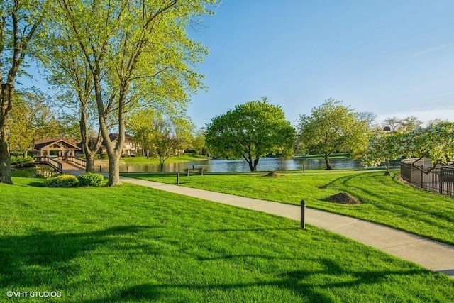 view of home's community with a water view and a lawn