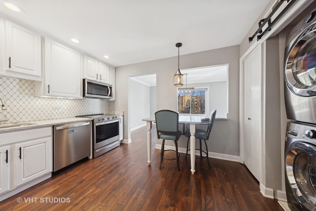 kitchen with appliances with stainless steel finishes, tasteful backsplash, sink, white cabinets, and stacked washer and clothes dryer