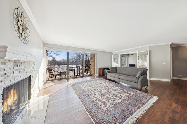 living room with crown molding, a stone fireplace, and wood-type flooring