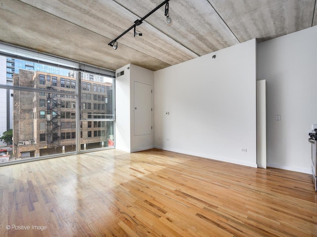 spare room featuring track lighting, hardwood / wood-style floors, and expansive windows