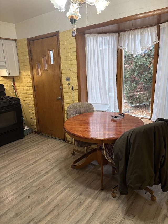 dining room with brick wall and light hardwood / wood-style flooring